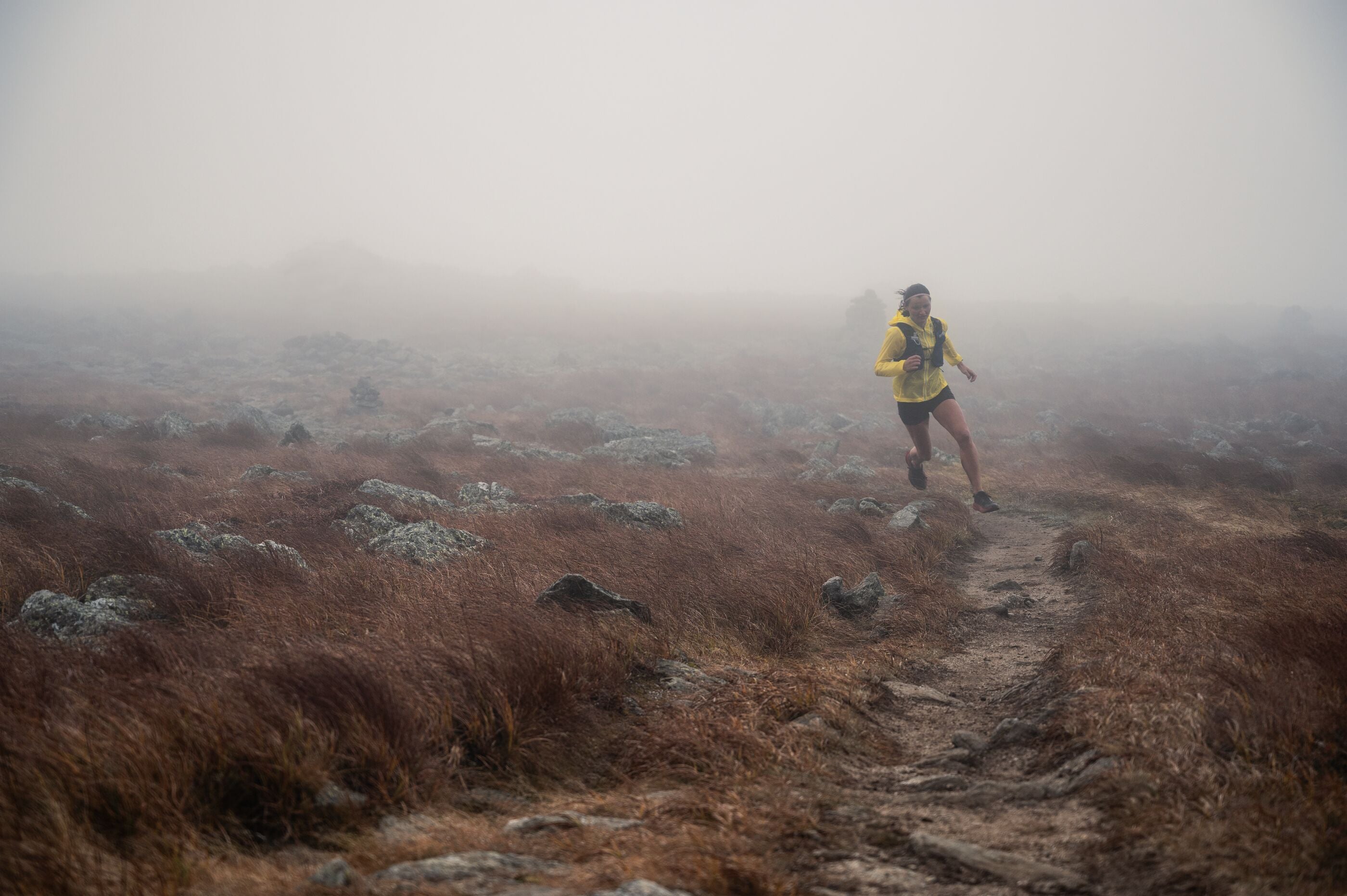 Woman running on a foggy trail in a natural landscape