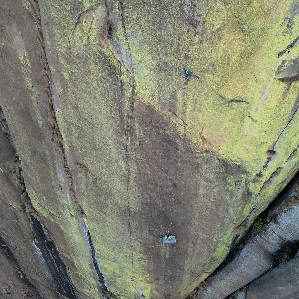 Two climbers on a steep, lichen-covered cliff face.