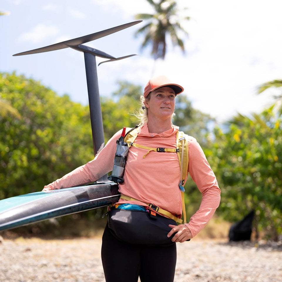 Person with a paddleboard on a beach with trees in the background
