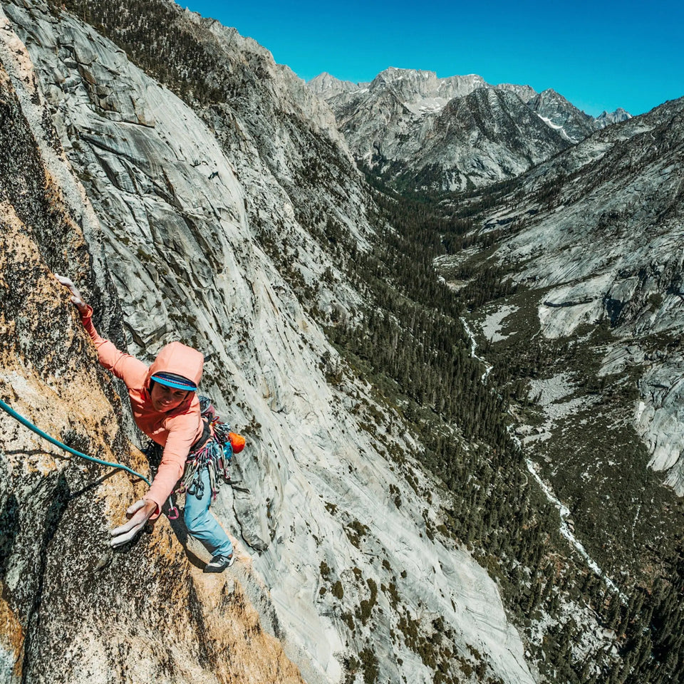 A woman rock climbing overlooking a scenic valley.