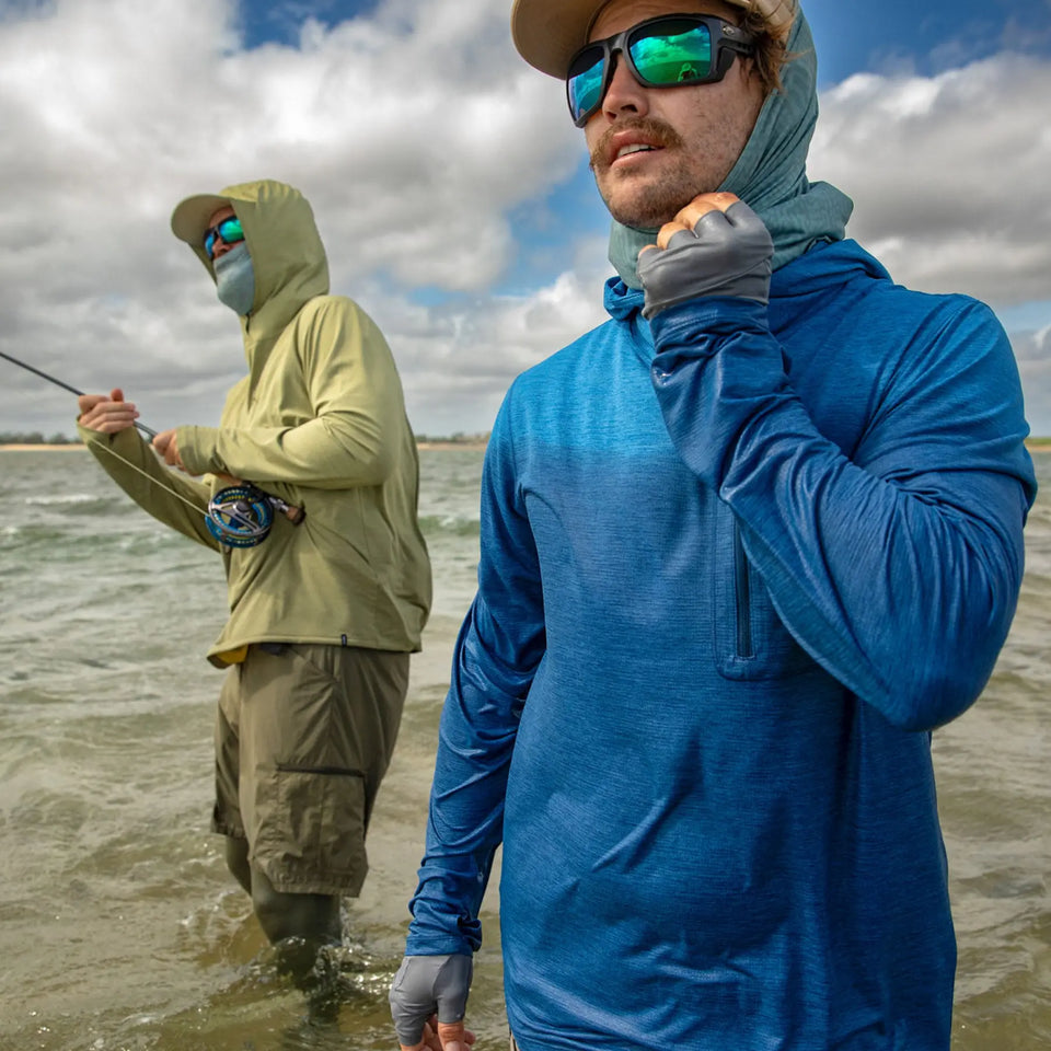 Two men fishing in water, one in a blue rain jacket and the other in a green raincoat.