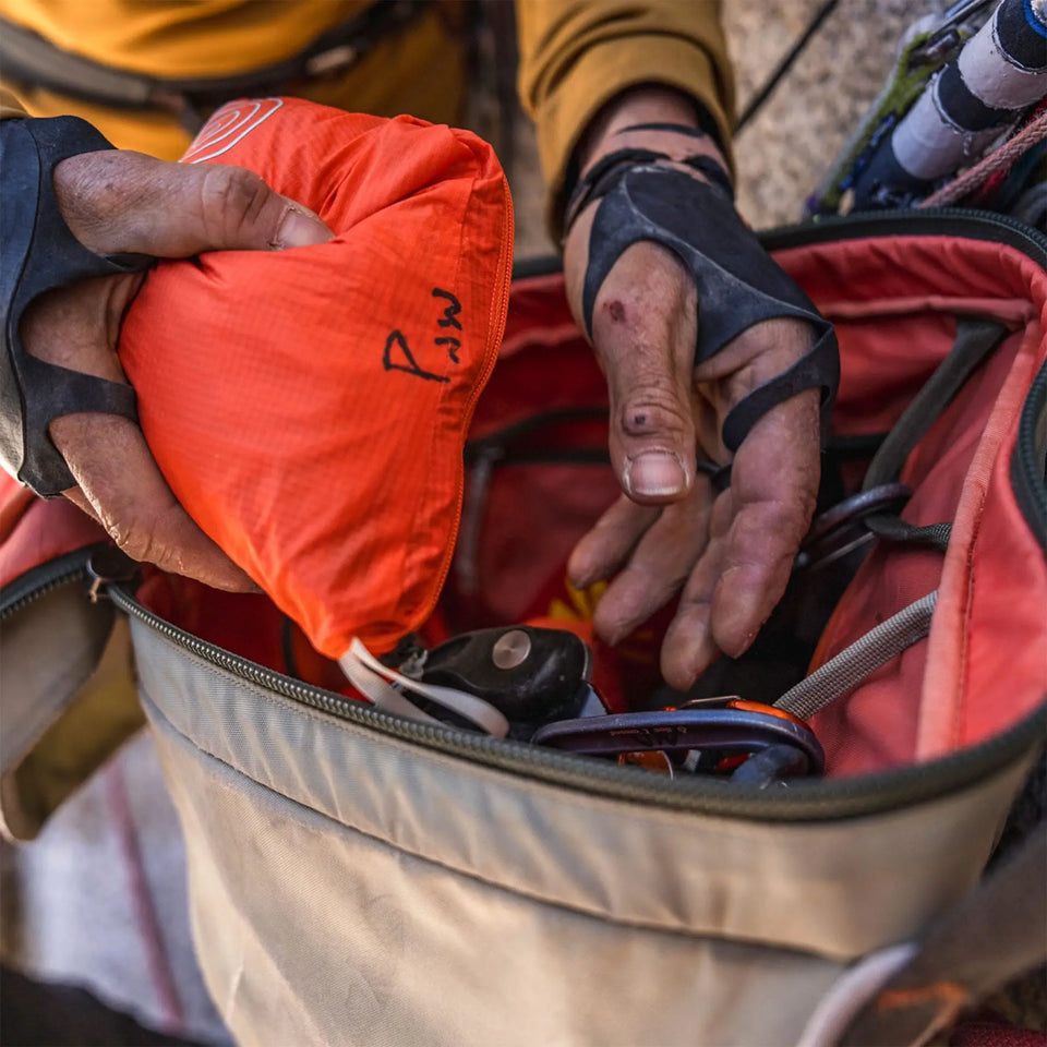 Person organizing items in a red backpack with an orange pouch