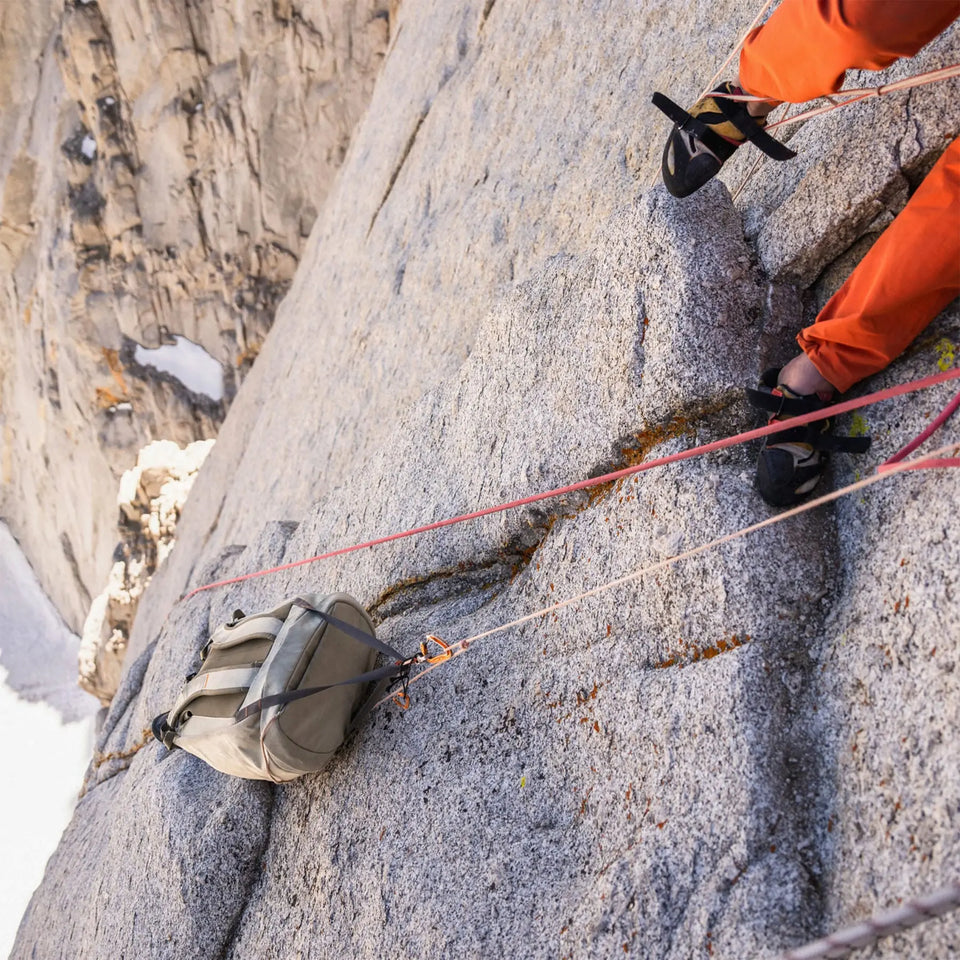 A tan pack getting hauled up a cliff.
