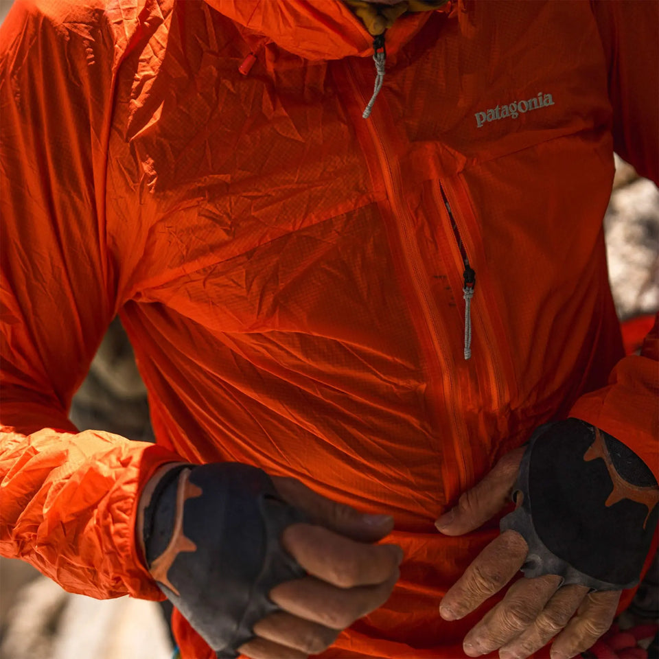 Person wearing an orange Patagonia jacket with gloves on, standing outdoors.