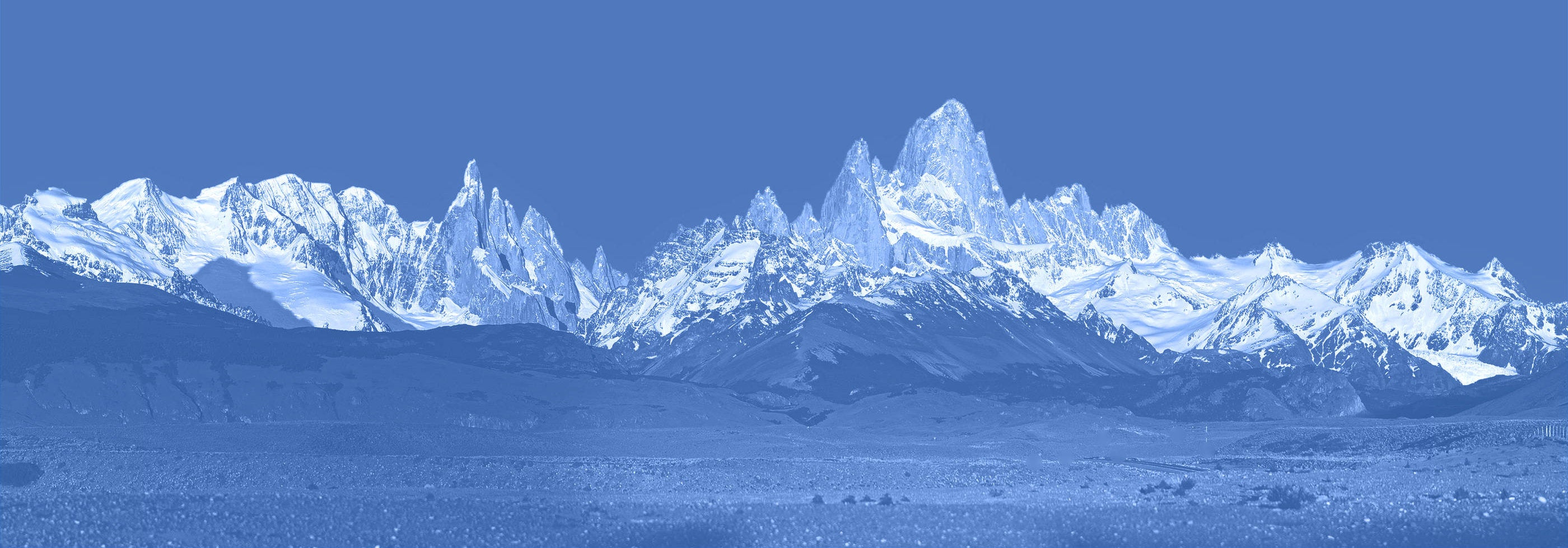 Panoramic view of snow-capped mountains under a blue sky